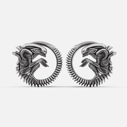 Pair of silver-tone alien invasion tunnels with ridged spine detail and coiled creature motif, front view