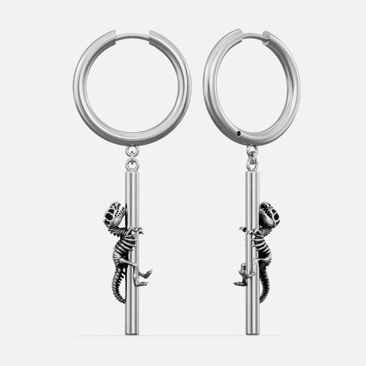 Silver-tone hoop earrings with a dangling dinosaur skeleton charm climbing a bar, shown as a pair