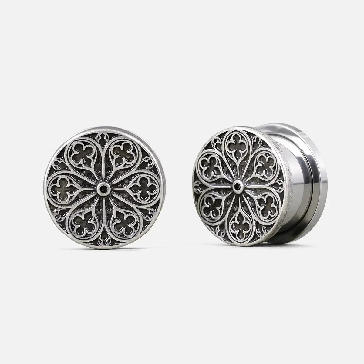 Pair of silver-tone ear plugs with a round cathedral rose window design, front and side view