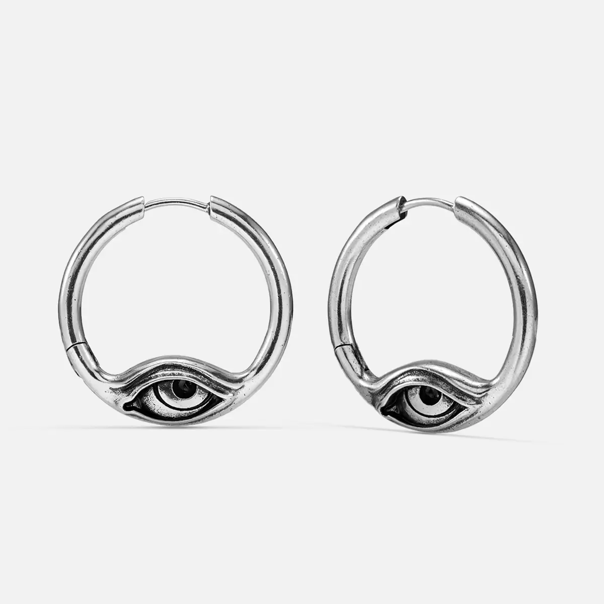 Eyelock Earrings in 925 sterling silver, pair shown on white, featuring sculpted eye motifs set into round silver hoops.