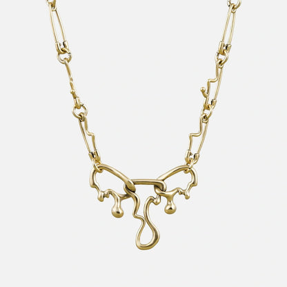 Gold-tone fluid pin necklace with a wavy paperclip chain and dripping abstract pendant, front view