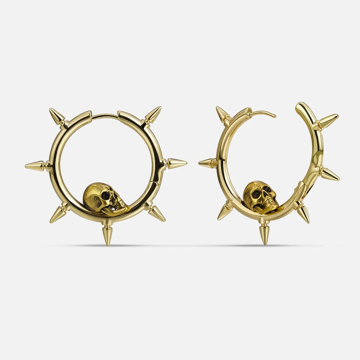 Gold-tone spiked hoop earrings featuring a skull charm nestled within each hoop