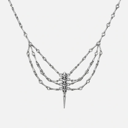 Silver-tone spine necklace with layered chains and a spike pendant, shown flat on a plain background