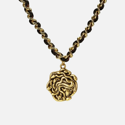 petrified power necklace in gold shown in a front close-up view, featuring a medusa-inspired pendant on a braided chain