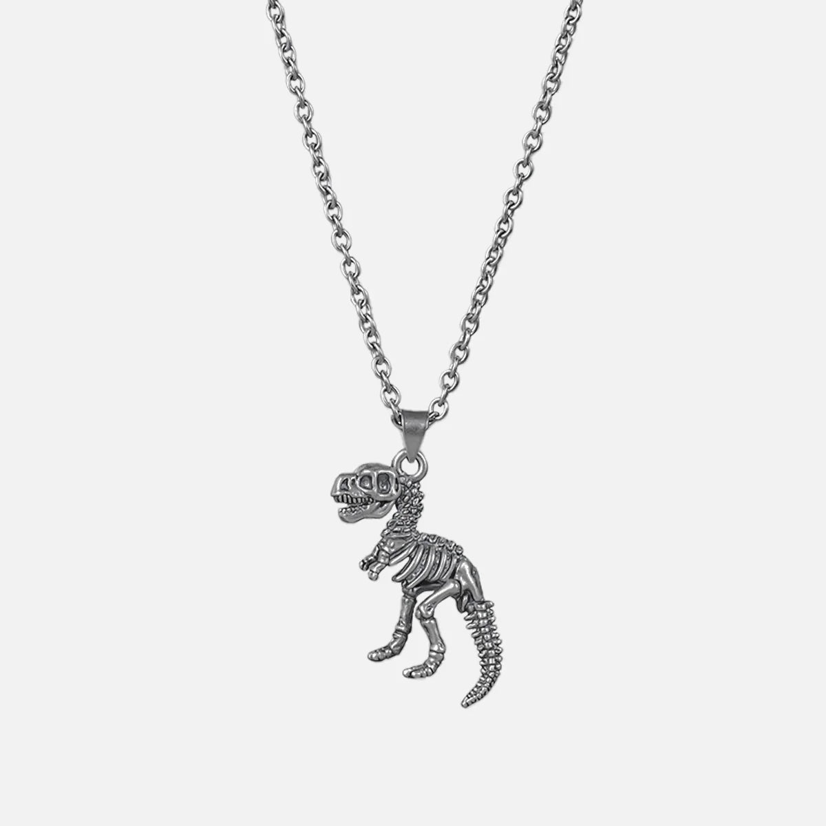 Silver-tone chain necklace with a dinosaur skeleton pendant shaped like a T-rex, laid flat