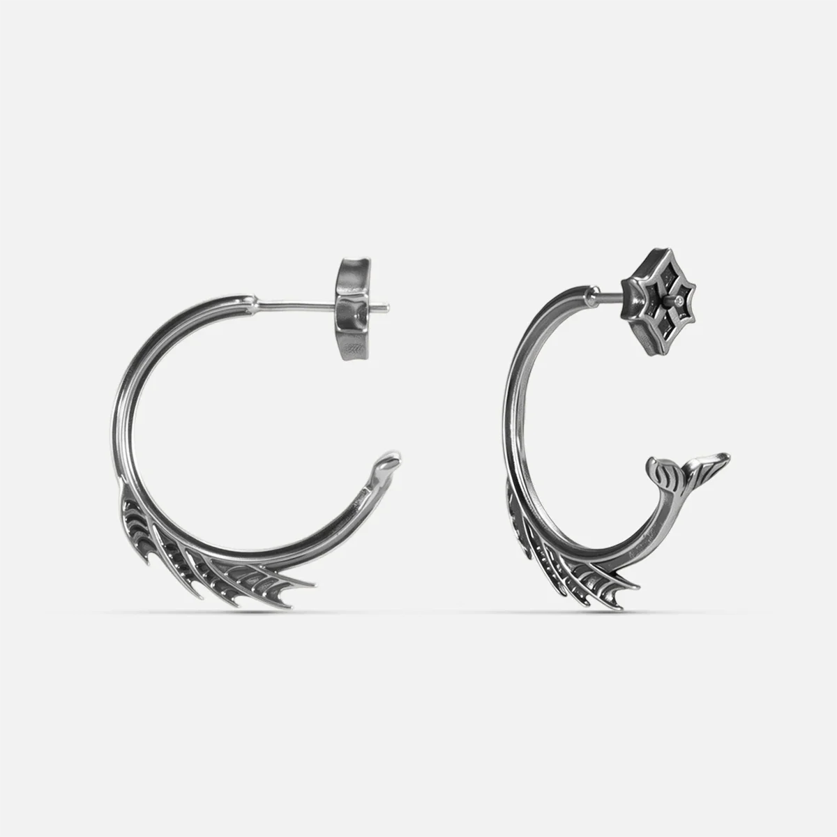Silver Siren Crest Earrings with fin-like ridges, sculptural half-hoop shape, and 925 silver posts on a clean background.