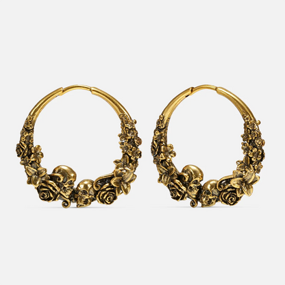 Pair of antique gold-tone hoop earrings with skull and rose blossom detailing, front view on white background
